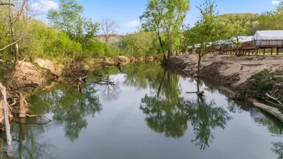 a river with trees and a building in the background at Furnished Glamping Tent/Red River Access/King Bed in Stanton
