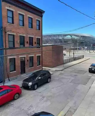 two cars parked in a parking lot next to a brick building at OTR by TQL+King Bed+Light Rail+Dedicated Parking in Cincinnati