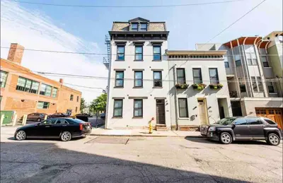 two cars parked in front of a white building at OTR by TQL+King Bed+Light Rail+Dedicated Parking in Cincinnati