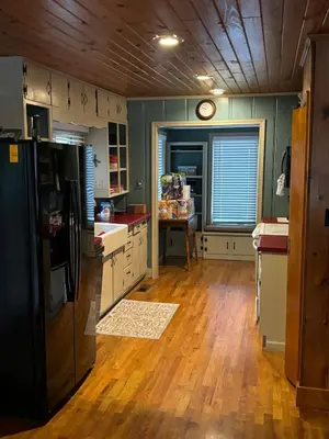 a kitchen with a black refrigerator and a wooden floor at House Upon a Hill in Newton Falls