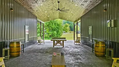 a barn with a table and barrels in a room at Sleeps 24/ 4 Kitchens / 4 Hot Tubs / 4 Firepits in Stanton