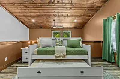 a bedroom with a bed with a green blanket at New/12 Guest /2 Hot Tubs/ 2 Kitchens/ 2 Firepits in Stanton