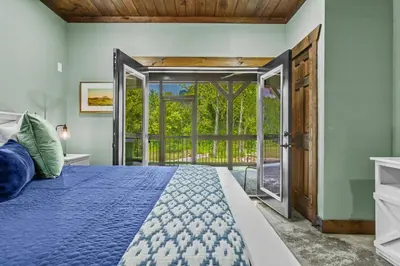 a bedroom with a bed and an open door at New/12 Guest /2 Hot Tubs/ 2 Kitchens/ 2 Firepits in Stanton