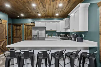 a kitchen with white cabinets and black chairs at New Barn/ Sleeps 12/ 2 Hot Tubs/ EV Charger in Stanton