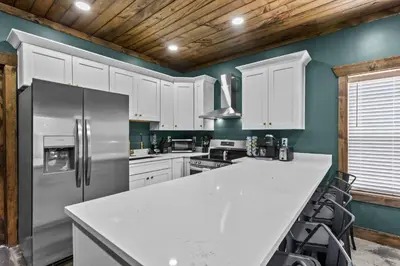 a kitchen with white cabinets and a stainless steel refrigerator at New Barn/ Sleeps 12/ 2 Hot Tubs/ EV Charger in Stanton
