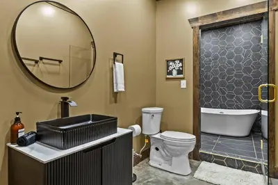 a bathroom with a toilet and a sink and a mirror at New Barn/ Sleeps 12/ 2 Hot Tubs/ EV Charger in Stanton
