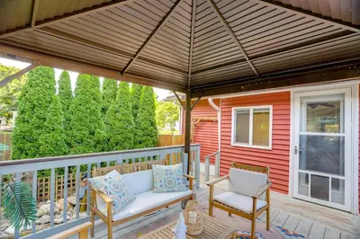 a porch with a wooden pergola and two chairs at Steps to Lake Erie! Cedar Point Home Base with Deck in Sandusky