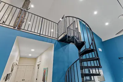a spiral staircase in a room with a blue wall at Barndo/Ample Parking/Access to Red River/Hot Tub in Stanton