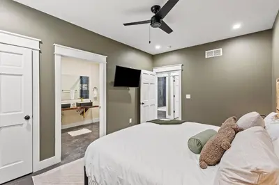 a bedroom with a white bed with a ceiling fan at New Barndo/Red River Access/King Beds/Hot Tub in Stanton