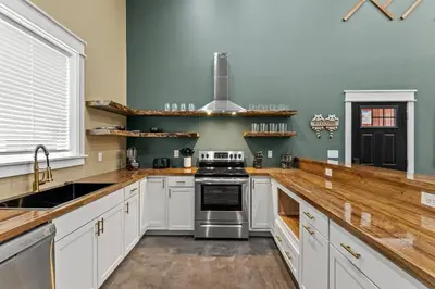 a kitchen with white cabinets and a stove top oven at New Barndo/Red River Access/King Beds/Hot Tub in Stanton