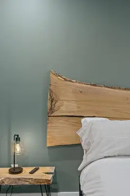 a bed with a wooden headboard and a table with a lamp at New Barndo/Red River Access/King Beds/Hot Tub in Stanton