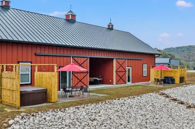 a red barn with a deck and a patio at New Barndo/Red River Access/King Beds/Hot Tub in Stanton