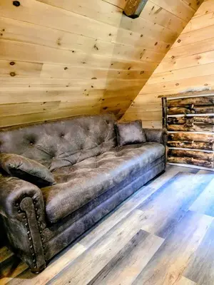 a brown leather couch in a room with a wooden ceiling at WildWood Cabin in Gambier