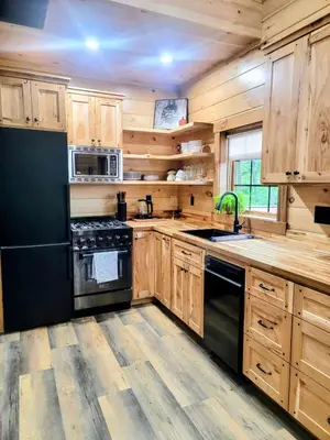 a kitchen with wooden cabinets and a black appliances at WildWood Cabin in Gambier