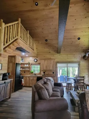 a living room with a couch and a kitchen at WildWood Cabin in Gambier