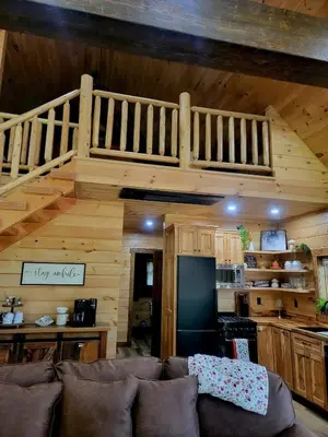 a living room with a couch and a loft at WildWood Cabin in Gambier