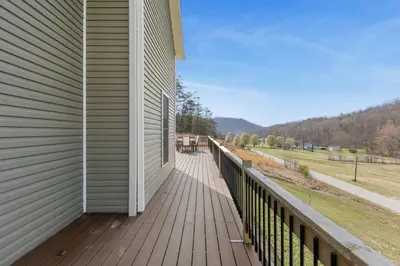 a wooden deck on a house with a view of a field at Arch Fun Lodge - Game Room, Theater, HotTub & View in Stanton