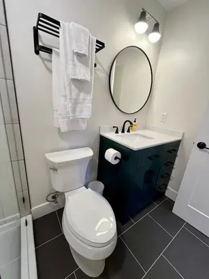 a bathroom with a toilet and a sink and a mirror at The Produce Suites in Toledo