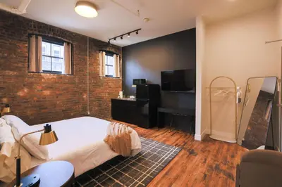a bedroom with a bed and a brick wall at The Produce Suites in Toledo