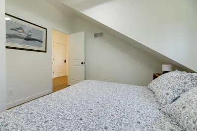 a white bedroom with a bed and a staircase at 1 Block to Loveland Bike Trail The Frog Man Inn in Loveland