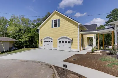 a yellow house with two white garage doors at Unique Studio on Obanyon Creek in Dtwn Loveland! in Loveland