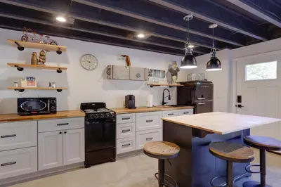 a kitchen with white cabinets and a island with bar stools at Unique Studio on Obanyon Creek in Dtwn Loveland! in Loveland