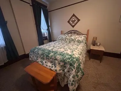 a bedroom with a bed with a floral comforter and a table at The Historic Hideaway in McConnelsville