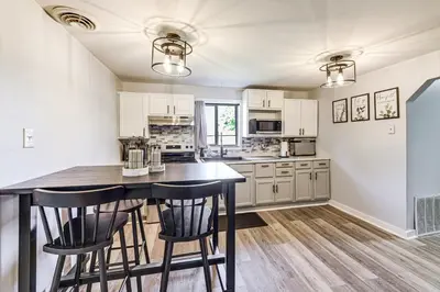 a kitchen with white cabinets and a table with chairs at Walk and Bike Great Miami River Trail Dayton Home in Dayton