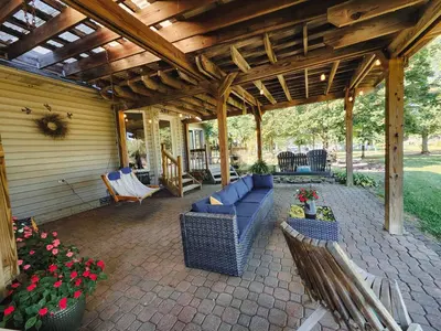 a patio with a blue couch and chairs under a wooden pergola at Spacious 5 bedroom 16 plus guests on 14 acres with fishing pond in Lagrange