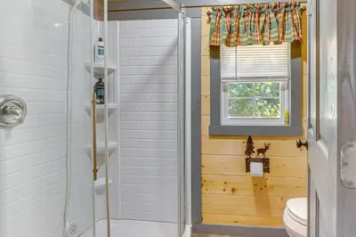 a bathroom with a shower and a toilet and a window at Charming Couples Cabin on 40 Acres in Zanesville in Zanesville