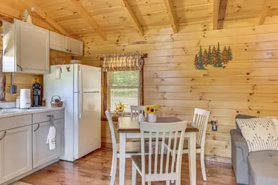 a kitchen and dining room with a table and a refrigerator at Charming Couples Cabin on 40 Acres in Zanesville in Zanesville
