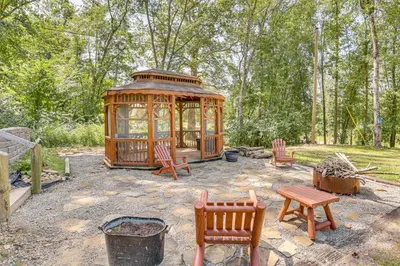 a wooden gazebo with chairs and a table and benches at Charming Couples Cabin on 40 Acres in Zanesville in Zanesville