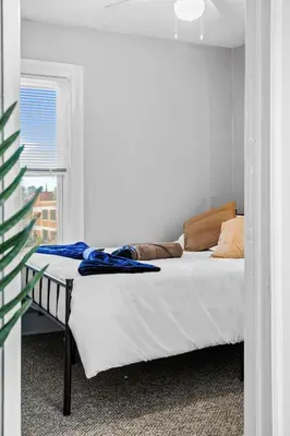 a white bed in a room with a window at Group Suite in Tremont, 4 TV's, Pet Friendly in Cleveland