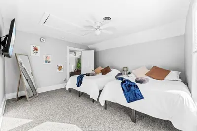 a white bedroom with two beds and a ceiling fan at Group Suite in Tremont, 4 TV's, Pet Friendly in Cleveland