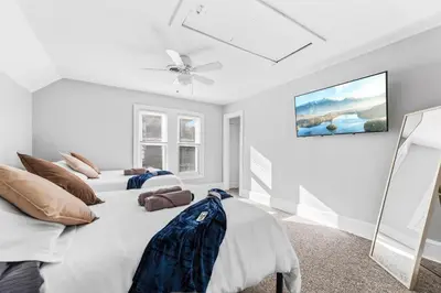 a white bedroom with two beds and a ceiling fan at Group Suite in Tremont, 4 TV's, Pet Friendly in Cleveland