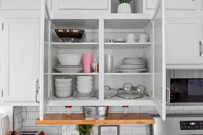a white cabinet with plates and dishes in it at Luxe Suite with Pool Table, King Bed, 3 TVs, & Free Parking in Cleveland