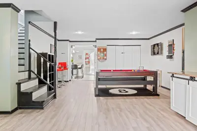 a living room with a pool table and stairs at Luxe Suite with Pool Table, King Bed, 3 TVs, & Free Parking in Cleveland