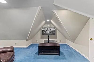 a living room with a couch and a television on a blue carpet at Ohio City 4 Bed 3 TV Free Parking Mins to DT in Cleveland
