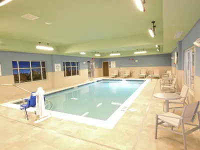 a large swimming pool with chairs and a table at Holiday Inn Express & Suites Toledo South - Perrysburg by IHG in Perrysburg Heights