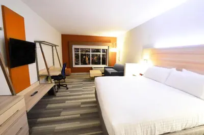 a hotel room with a large bed and a living room at Holiday Inn Express & Suites Toledo South - Perrysburg by IHG in Perrysburg Heights