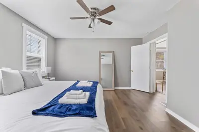 a white bedroom with a large bed with a ceiling fan at KING Bed Entire House Near DT in Cleveland