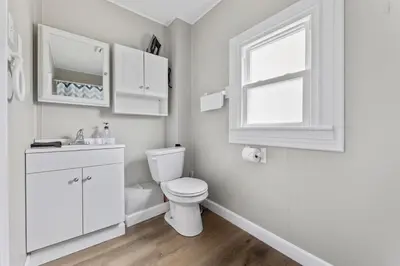 a white bathroom with a toilet and a window at KING Bed Entire House Near DT in Cleveland
