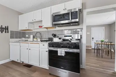 a kitchen with white cabinets and a black stove top oven at KING Bed Entire House Near DT in Cleveland