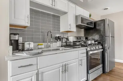 a kitchen with white cabinets and a stainless steel refrigerator at Luxe Mattresses Pet Friendly Free Prkng WiFi in Cleveland