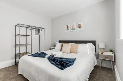 a bedroom with a large white bed and a night stand at Little Italy Family Suite 4 TVs Bunk Beds in Cleveland