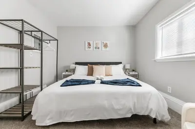 a white bedroom with a large white bed and a shelf at Little Italy Family Suite 4 TVs Bunk Beds in Cleveland