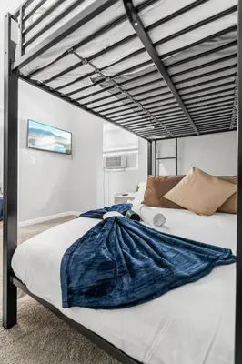 a bed with a blue blanket on top of it at Little Italy Family Suite 4 TVs Bunk Beds in Cleveland