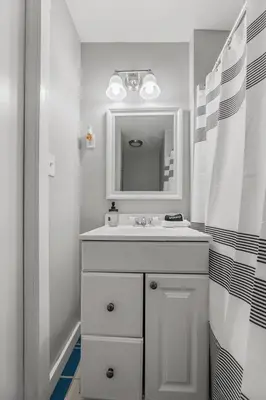 a white bathroom with a sink and a mirror at King Bed 2 TVs Fast Wifi Pet Friendly! in Cleveland