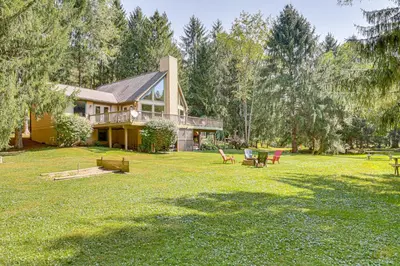 a house on a lawn with chairs in front of it at 23 Mi to Mohican SP Group-Ready Lodge with Hot Tub in Brinkhaven
