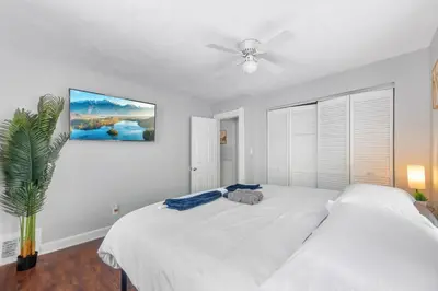 a bedroom with a white bed and a ceiling fan at Little Italy Group Stay 4 TV's Pet Friendly in Cleveland